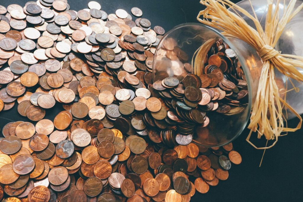Coins spilling from a glass jar symbolizing saving money, budgeting, and personal finance management.